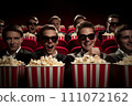 Friends having a great time watching a film and munching on popcorn together in the cinema 111072162