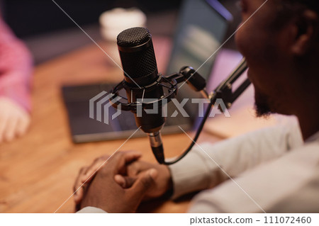 Close up shot of black professional microphone and African American man recording podcast in studio Close up shot of black professional microphone and African American man recording podcast in studio 111072460