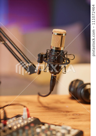 Vertical close up shot of gold studio microphone on stand with equipment prepared for live podcast in studio Vertical close up shot of gold studio microphone on stand with equipment prepared for live podcast in studio 111072464
