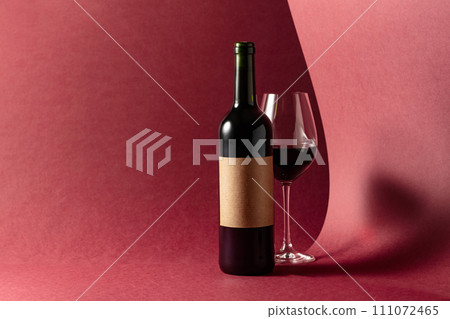 Bottle and glass of red wine on a red background. 111072465