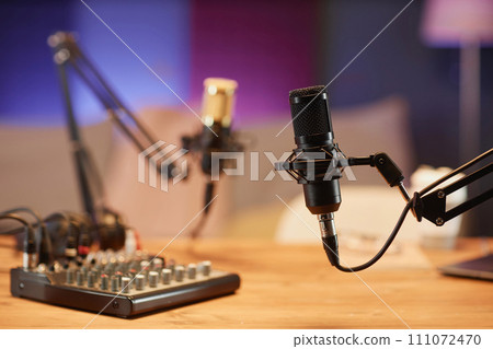Medium shot with selective focus on black professional microphone and sound mixer on table in podcast room Medium shot with selective focus on black professional microphone and sound mixer on table in podcast room 111072470