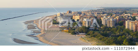 Aerial shot of sandy beach with parasol and on right Lido Adriano town Aerial shot of sandy beach with parasol and on right Lido Adriano town 111072944