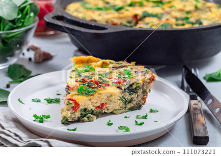 Piece of brunch egg frittata with vegetables on plate, horizontal Piece of brunch egg frittata with vegetables on plate, horizontal 111073221