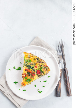 Piece of brunch egg frittata with vegetables on plate, vertical, top view, copy space Piece of brunch egg frittata with vegetables on plate, vertical, top view, copy space 111073228