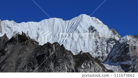 Blue sky over a high white mountain in the Himalayas, view from Gorakshep, Nepal. 111073662