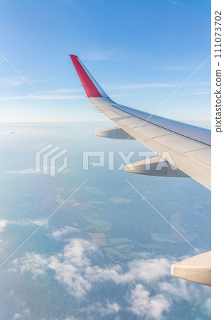 View from the airplane window at a beautiful cloudy sky and the airplane wing 111073702