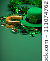 St. Patrick's Day Leprechaun Hat, Gold Coins, Shamrocks and Party Favors on Green Background. 111074762
