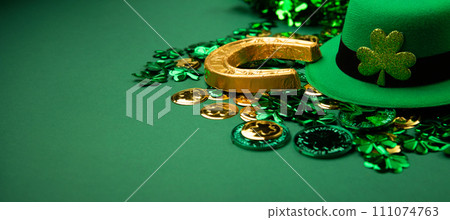St. Patrick's Day Leprechaun Hat, Gold Coins, Shamrocks and Party Favors on Green Background. St. Patrick's Day Leprechaun Hat, Gold Coins, Shamrocks and Party Favors on Green Background. 111074763