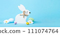 White Wooden Easter Bunny, Chocolate Eggs and Spring Flowers on Blue Background 111074764