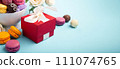 Macaroons, Gift Box, Rose Flowers and Chocolate Candies on Blue Background. Spring Presents Concept 111074765