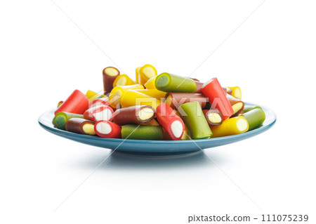 Sweet colorful chewy candy sticks on plate isolated on white background. Sweet colorful chewy candy sticks on plate isolated on white background. 111075239