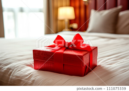 Red gift box with gold ribbon on bed decoration in hotel bedroom interior 111075339