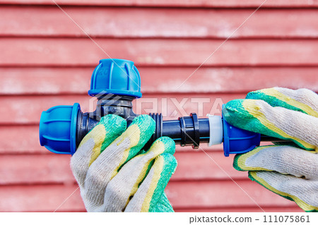 Joint tee plastic pipe fitting with section of HDPE pipe for drinking and irrigation water supply, worker hands hold structure. Joint tee plastic pipe fitting with section of HDPE pipe for drinking and irrigation water supply, worker hands hold structure. 111075861