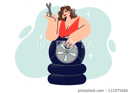 Woman auto mechanic leans over wheels and demonstrates wrench for self-repairing car Woman auto mechanic leans over wheels and demonstrates wrench for self-repairing car 111075886