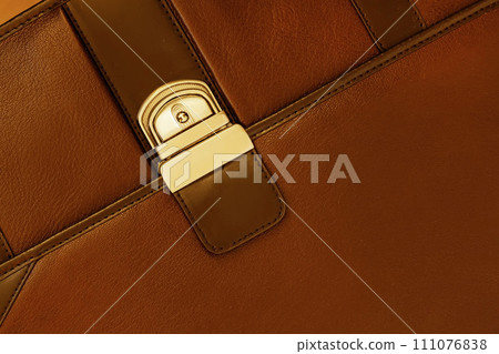 Briefcase from genuine leather close-up, texture. Detail of leather briefcase, metal clasp, background 111076838