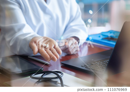 Doctor holds pills for treatment in his palm at the table. Doctor holds pills for treatment in his palm at the table. 111076969