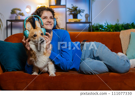 Joyful relaxed woman listening to smartphone music through wireless headphones lying on sofa dancing Joyful relaxed woman listening to smartphone music through wireless headphones lying on sofa dancing 111077330