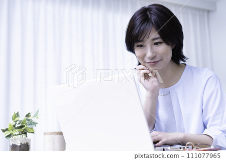 A young woman using a laptop in a sunny room 111077965