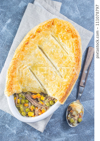 Beef pot pie or deep dish pie in baking dish, crust broken open, vertical, top view Beef pot pie or deep dish pie in baking dish, crust broken open, vertical, top view 111078797