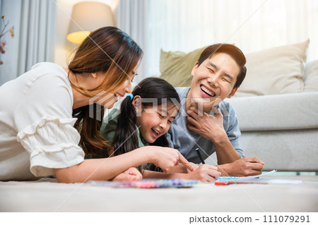Smiling Father, Mother and daughter drawing together on paper at home, Asian family lying on floor painting with child daughter in living room, Happy family activity enjoy, learning draw art picture 111079291