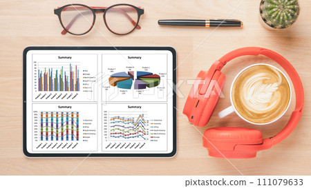 A contemporary work desk displaying a tablet with intricate business analytics, complemented by stylish eyewear, vibrant headphones, and a perfect cup of cappuccino. A contemporary work desk displaying a tablet with intricate business analytics, complemented by stylish eyewear, vibrant headphones, and a perfect cup of cappuccino. 111079633