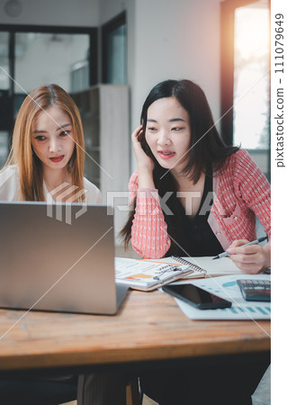 Two attentive businesswomen analyze and discuss data on a laptop screen, deeply focused on developing business insights in an office setting. Two attentive businesswomen analyze and discuss data on a laptop screen, deeply focused on developing business insights in an office setting. 111079649