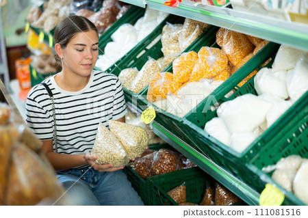 Young girl is in department of market with packaged products and is thinking about what to choose Young girl is in department of market with packaged products and is thinking about what to choose 111081516