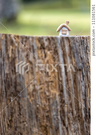 A small house with a cute rustic chimney made of unglazed earthenware placed on a log stump. 111081561