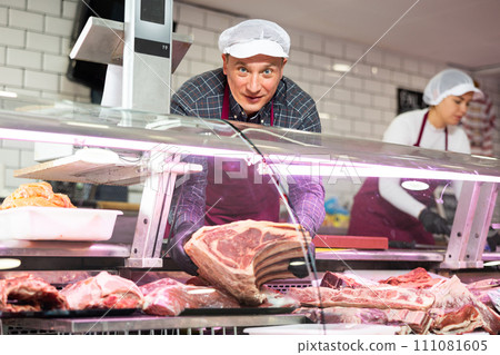 Smiling butcher offering piece of raw beef chop on ribs 111081605
