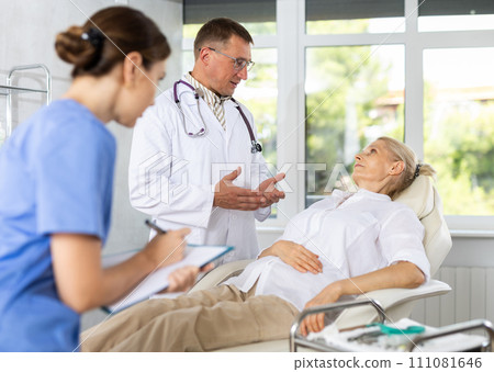 Female nurse and male doctor carries out survey of mature female patient about allergic reactions 111081646