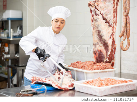 Young woman butcher sawing beef ribs 111081734