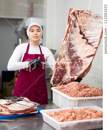 Young butcher shop saleswoman offering fresh raw beef 111081832