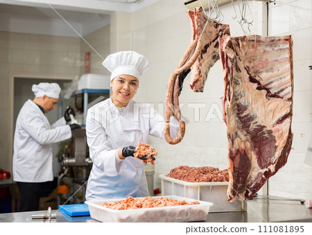 Young woman butcher holding meat sausages 111081895