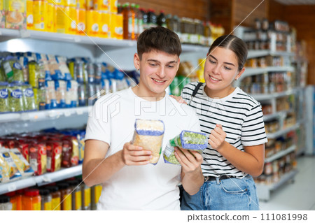 Young married couple carefully checks the information on product labels in hypermarket Young married couple carefully checks the information on product labels in hypermarket 111081998