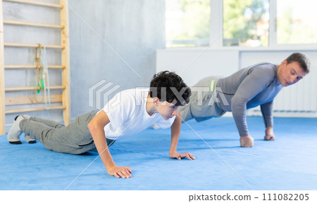 Man and teenage boy train their abs 111082205