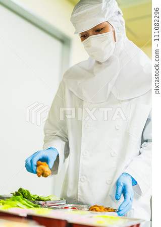一位穿著乾淨西裝的年輕女子裝著配菜 一位穿著乾淨西裝的年輕女子裝著配菜 111082296