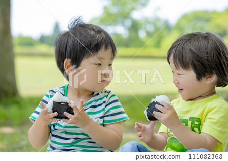 Boys eating rice balls in the park Boys eating rice balls in the park 111082368