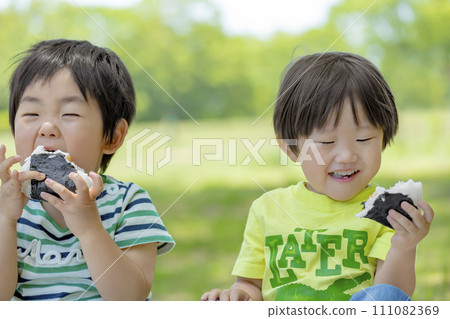 Boys eating rice balls in the park Boys eating rice balls in the park 111082369