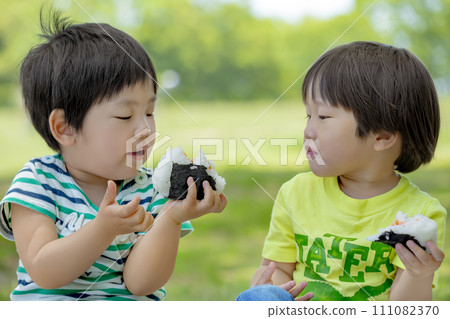 Boys eating rice balls in the park Boys eating rice balls in the park 111082370