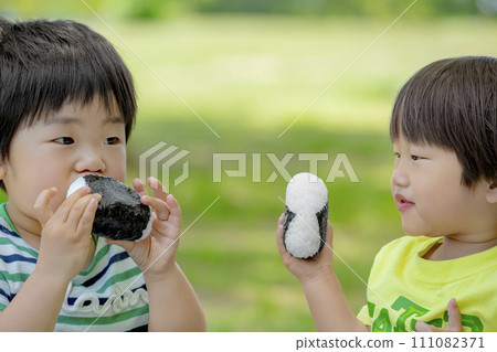 Boys eating rice balls in the park Boys eating rice balls in the park 111082371