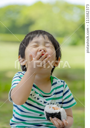 Boy eating rice balls in the park 111082373