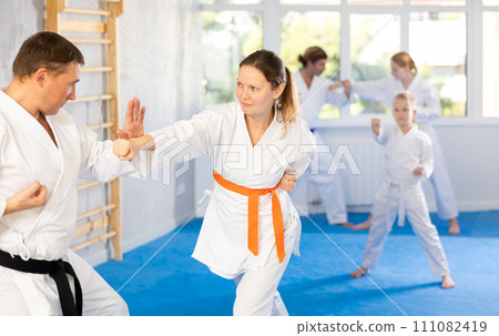 Woman is paired with man teacher to learn how to strike and rehearses blocking opponent Woman is paired with man teacher to learn how to strike and rehearses blocking opponent 111082419