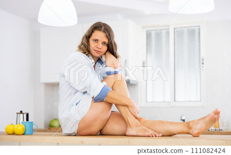 Beautiful young girl in shirt sitting on table Beautiful young girl in shirt sitting on table 111082424