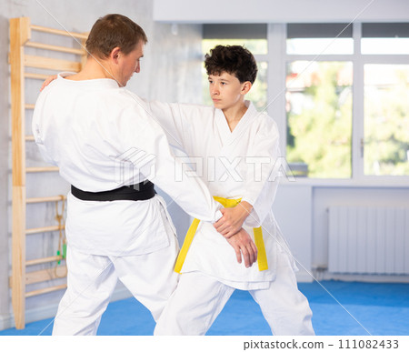 Coach teaches judo techniques to teenager during individual training Coach teaches judo techniques to teenager during individual training 111082433
