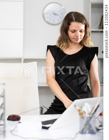 Portrait of female manager standing at her desktop 111082434