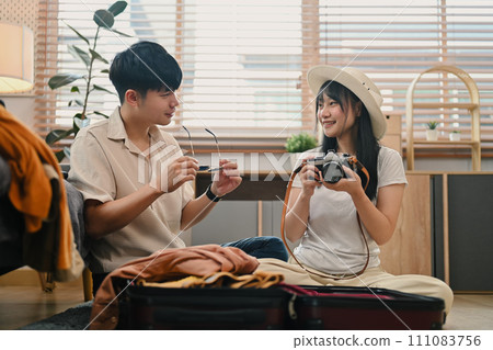Lovely young couple preparing clothes, getting ready for honeymoon holiday trip Lovely young couple preparing clothes, getting ready for honeymoon holiday trip 111083756