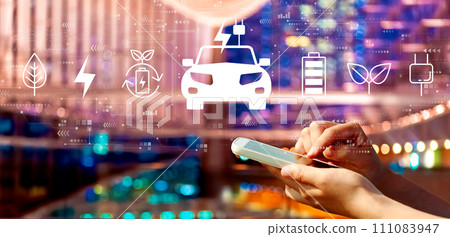 EV concept with person using a smartphone in city at night EV concept with person using a smartphone in city at night 111083947