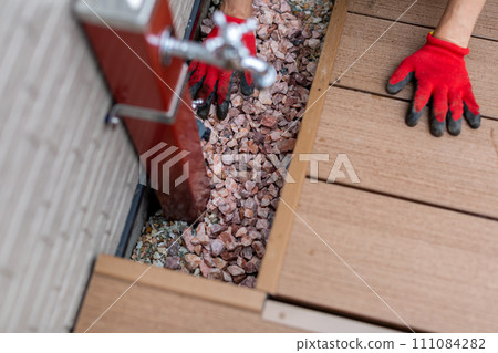 A man laying gravel in the garden, gardening 111084282