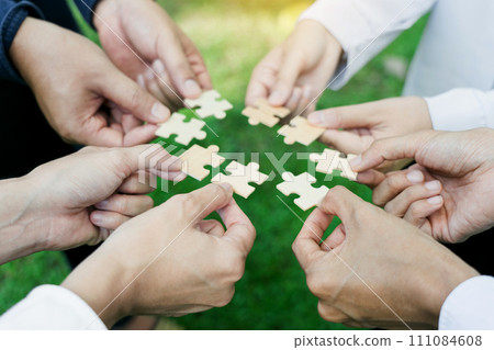 group of business people assembling jigsaw puzzle. The concept of cooperation, teamwork, help and support in business. 111084608