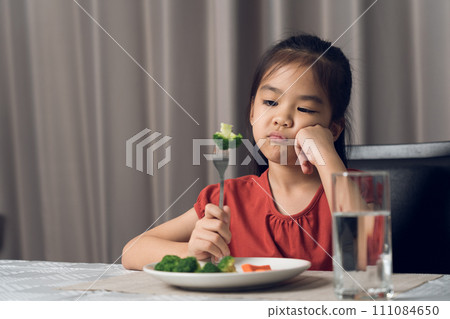 Little cute kid girl refusing to eat healthy vegetables. Children do not like to eat vegetables. Little cute kid girl refusing to eat healthy vegetables. Children do not like to eat vegetables. 111084650